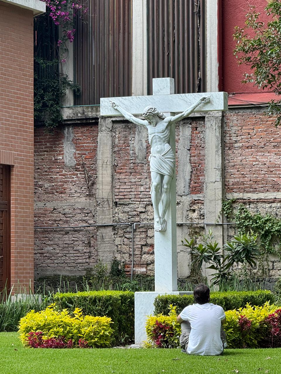 Joven sentado en el jardín contemplando el crucifijo